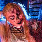 Scary doll character at Factory of Terror Haunted House with eerie lighting.