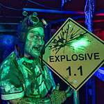 Character with explosive sign at Factory of Terror Haunted House with green and blue lighting
