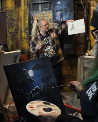 Instructor guiding a Paint Night class while guest paints a nighttime canvas at Factory of Terror Fall River MA